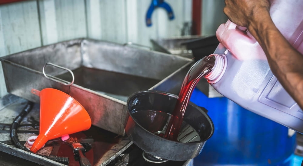 A can of transmission fluid being poured into a funnel.