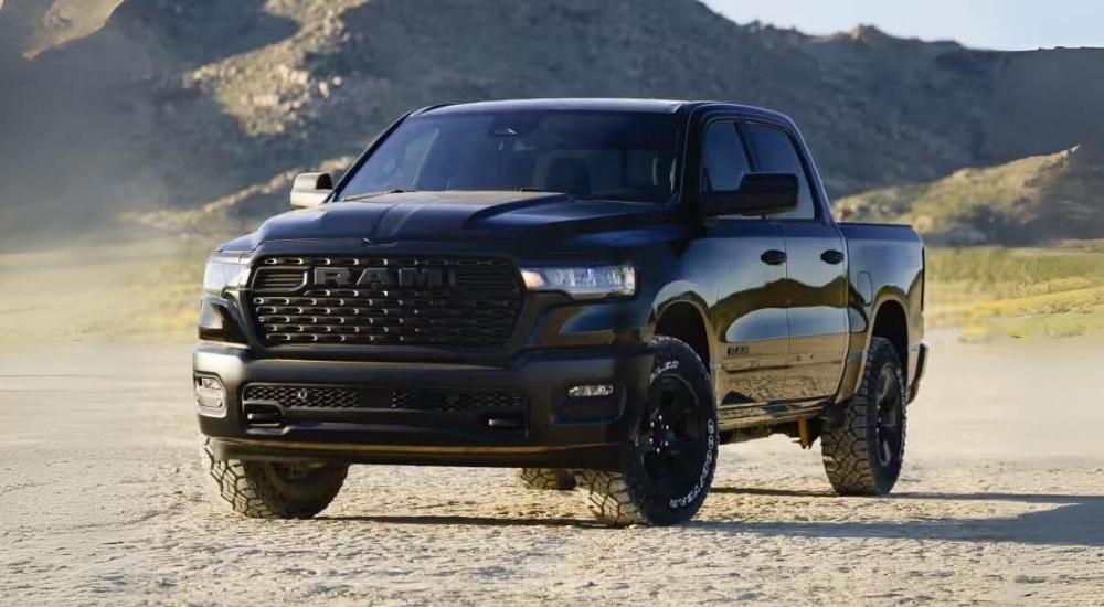 A black 2025 Ram 1500 Warlock is shown parked on sand.