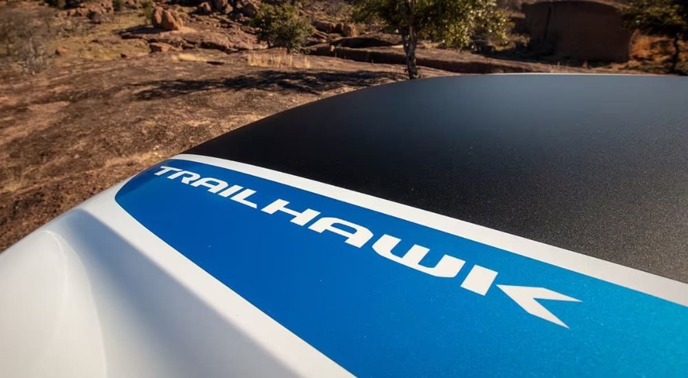 A close-up shows the Trailhawk decal on the hood over a silver 2024 Jeep Grand Cherokee 4xe Trailhawk.