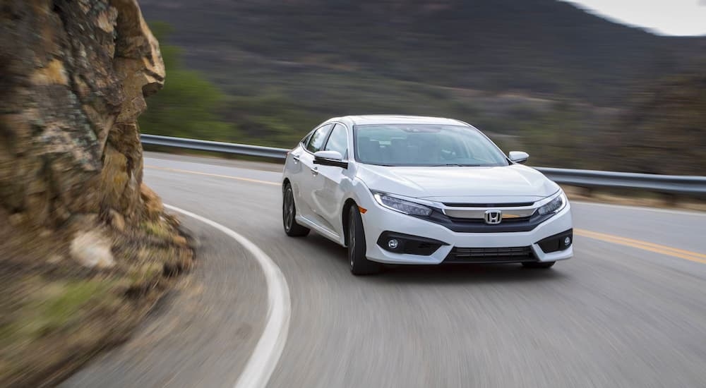 A white 2018 Honda Civic driving around a bend.