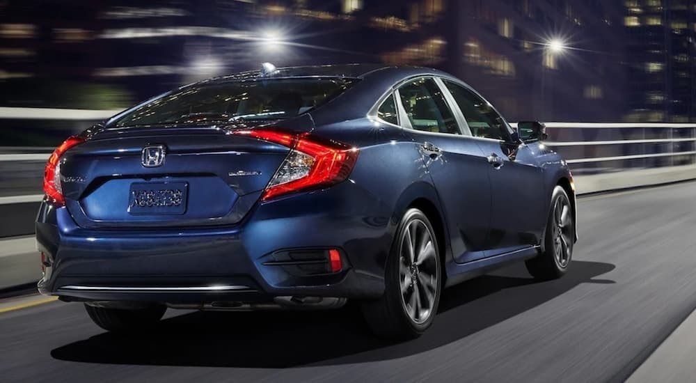 Rear view of a blue 2021 Honda Civic driving in a city.