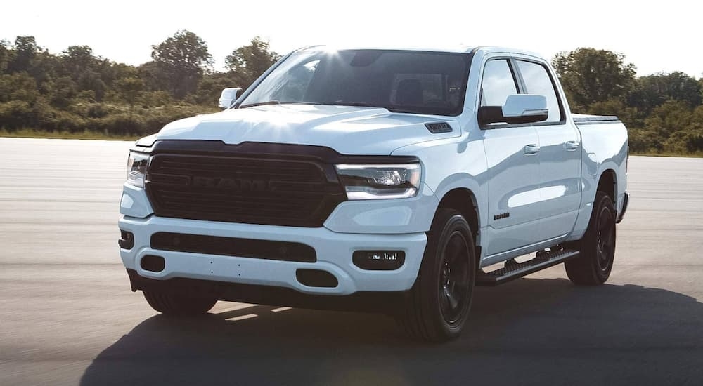 A white 2020 Ram 1500 is shown driving on pavement.