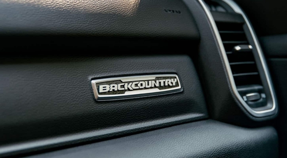 A close-up shows the 'BackCountry' badge on the black dash of a 2023 Ram 1500 Big Horn BackCountry.