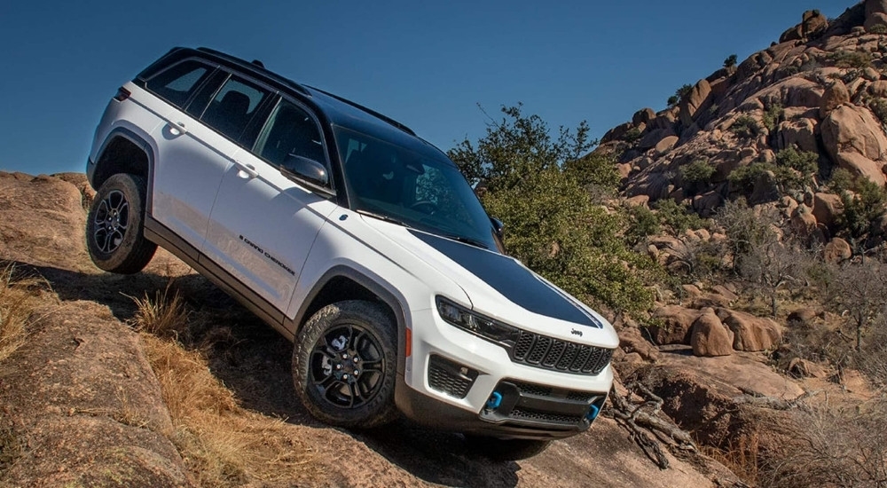 A white 2024 Jeep Grand Cherokee 4xe Trailhawk is shown off-roading.