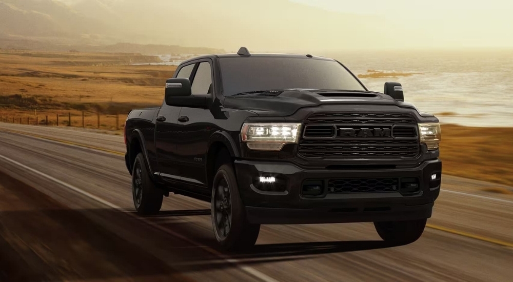 A black 2024 Ram 3500 is shown driving on an open road.