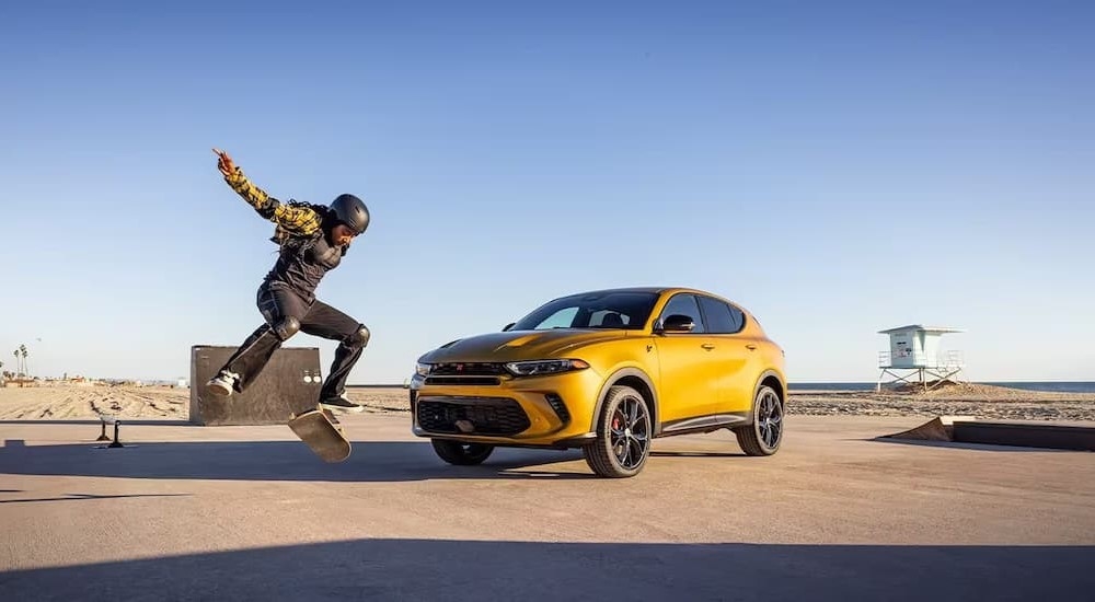 A person is shown skateboarding near a gold 2024 Dodge Hornet.