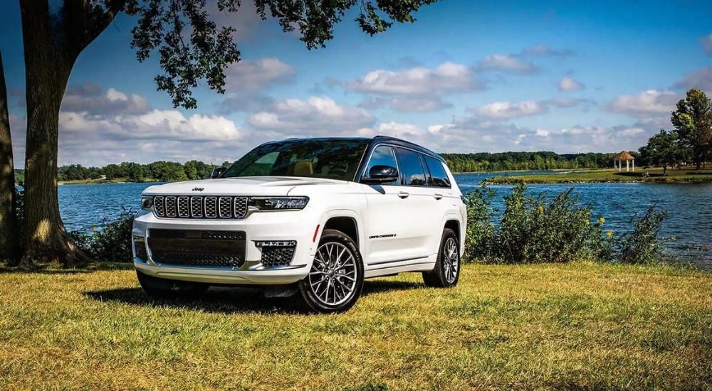 A white 2024 Jeep Grand Cherokee for sale is shown parked near a lake.