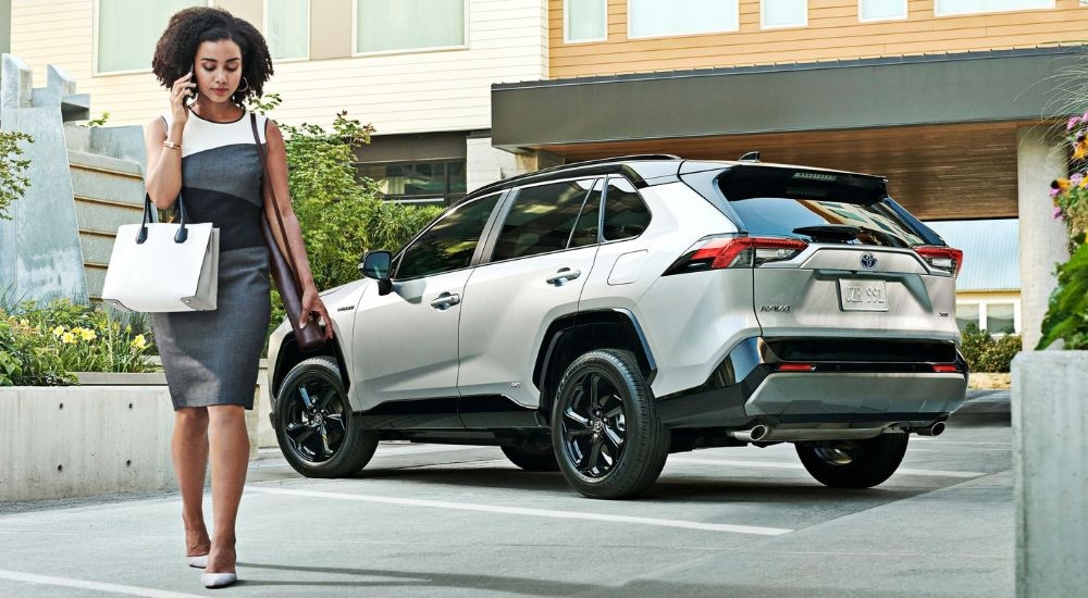 Rear view of a white 2024 Toyota RAV4 Hybrid parked and angled left.