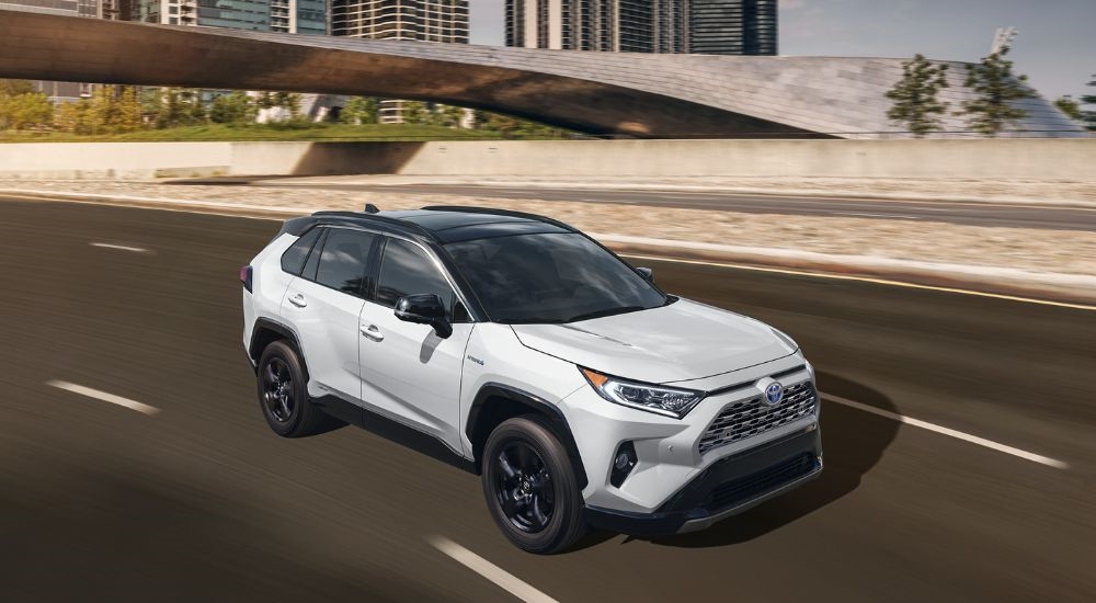 A white 2024 Toyota RAV4 Hybrid driving under a bridge.