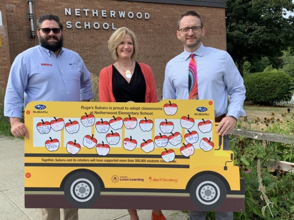 Three people near a school bus display.