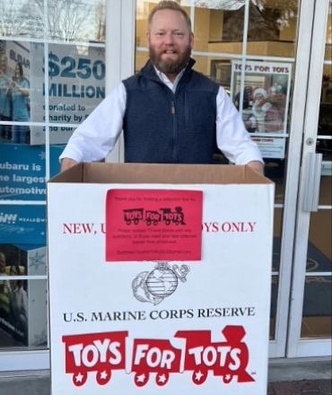 A person holding a Toys for Tots box.