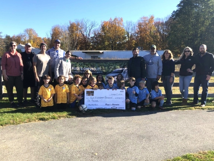A soccer team holding a giant check.