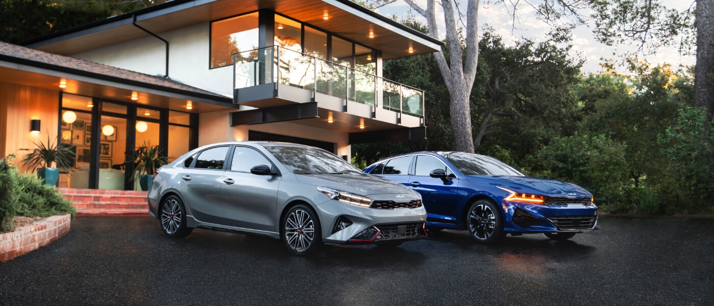 Two 2025 Kia K5 cars parked by a house