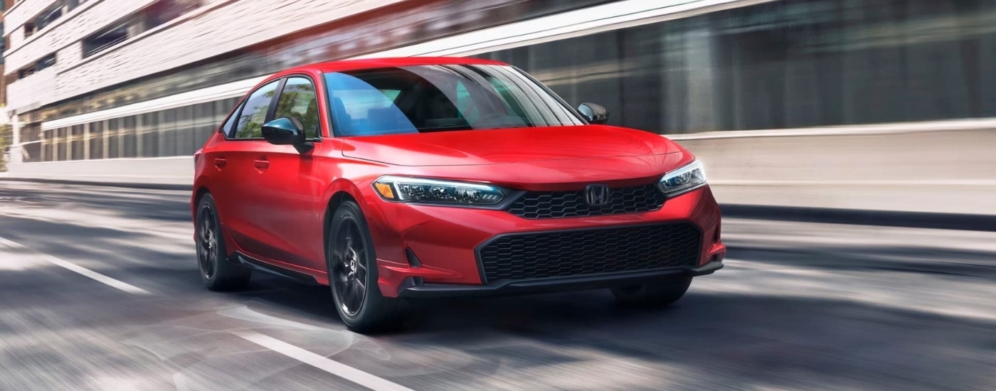 A red 2025 Honda Civic Sport is shown driving on a city street.