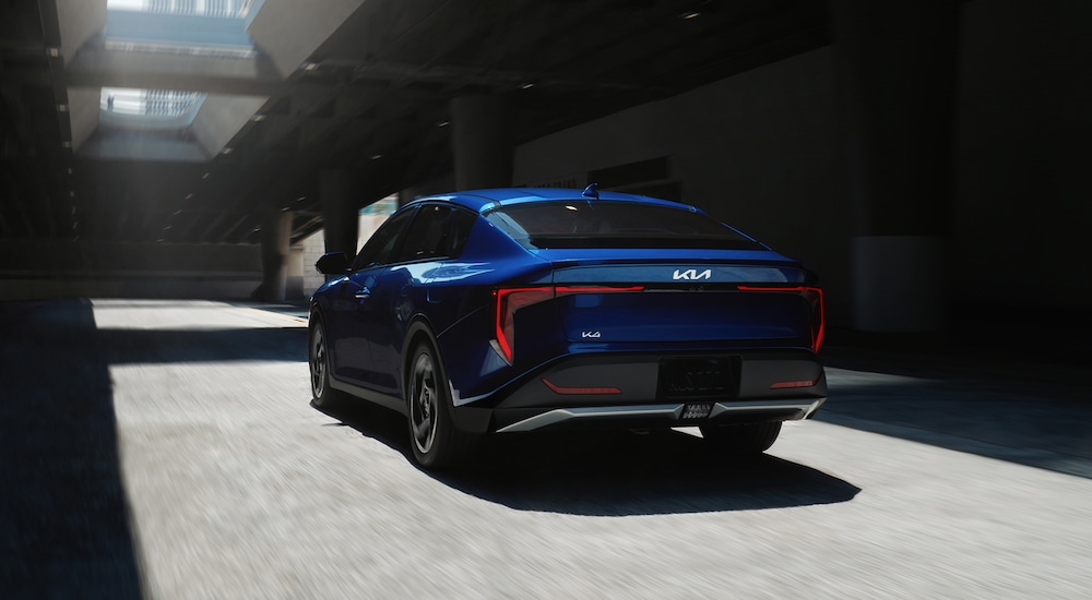 Rear angle view of a blue 2025 Kia K4 driving through a tunnel.