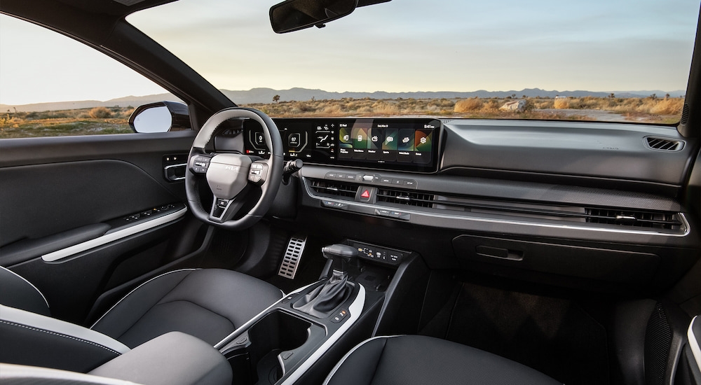 The grey interior of a 2025 Kia K4, featuring the steering wheel and dashboard interface.