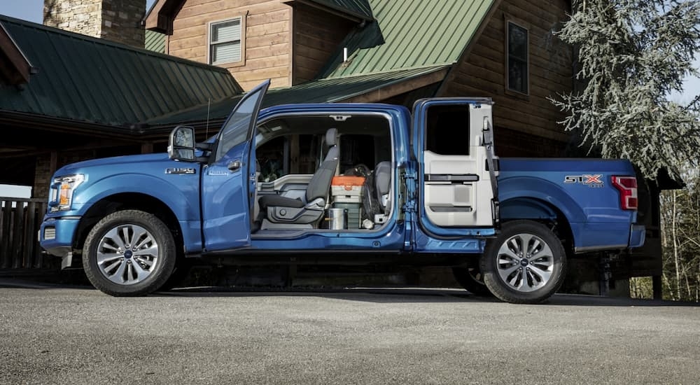 Side angle view of a blue 2024 Ford F-150 with open doors.