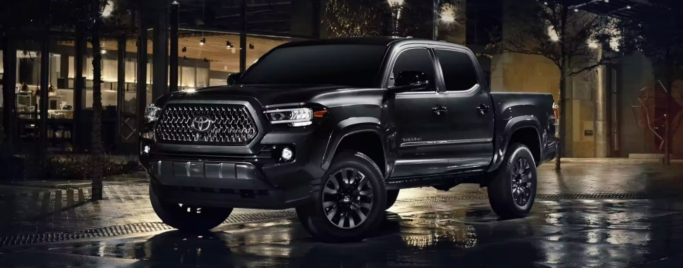 A black 2023 Toyota Tacoma Limited Nightshade Edition is shown on a city street at night.