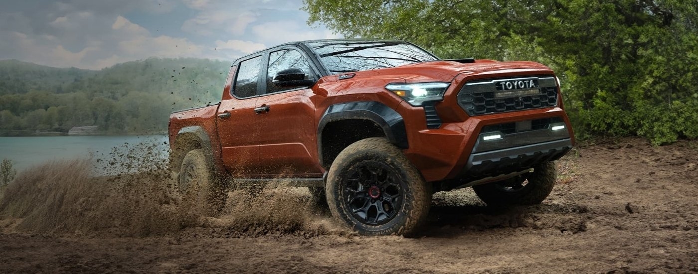 A red 2024 Toyota Tacoma TRD Pro is shown kicking up dust.