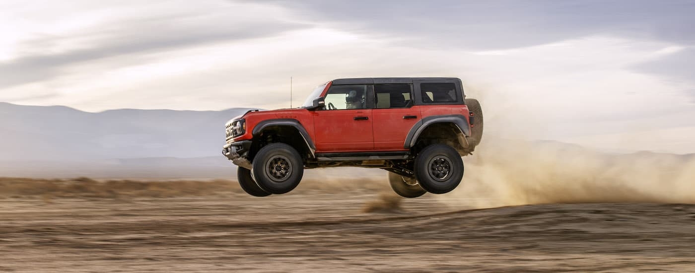 A red 2023 Ford Bronco Raptor is shown from the side.