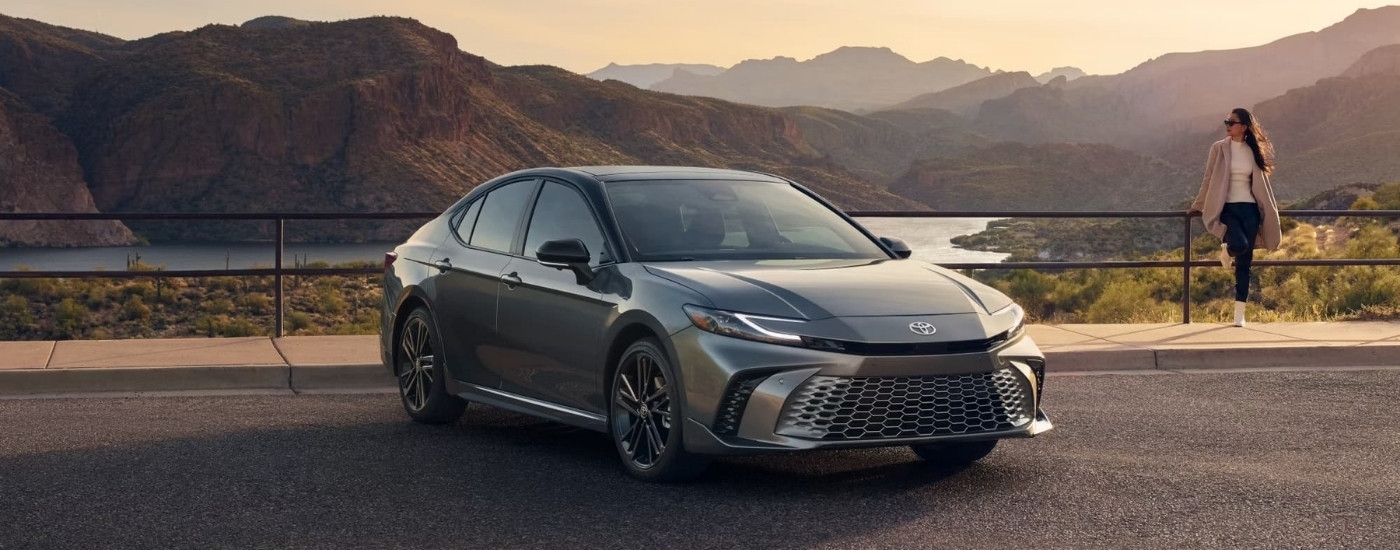 A grey 2025 Toyota Camry XSE is shown parked overlooking mountains.