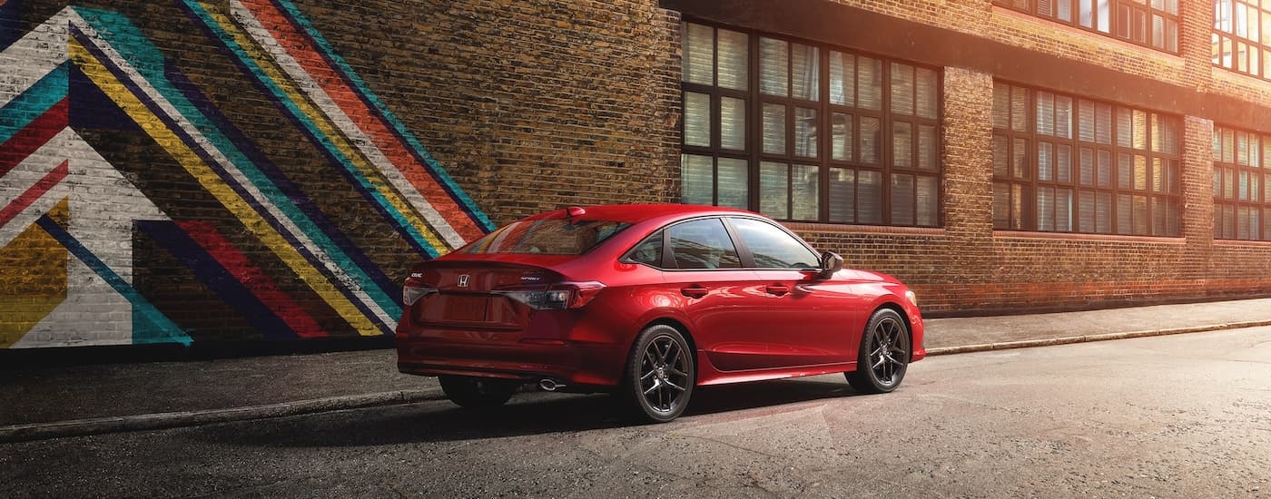 Rear view of a red 2022 Honda Civic Sport parked by a brick wall.