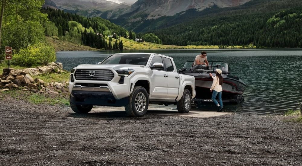 A white 2024 Toyota Tacoma Limited towing a boat out of a lake.