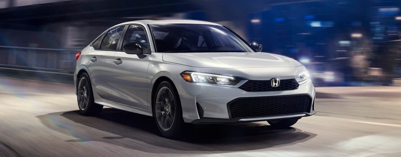 A white 2025 Honda Civic for sale near Lynnwood driving in a city.