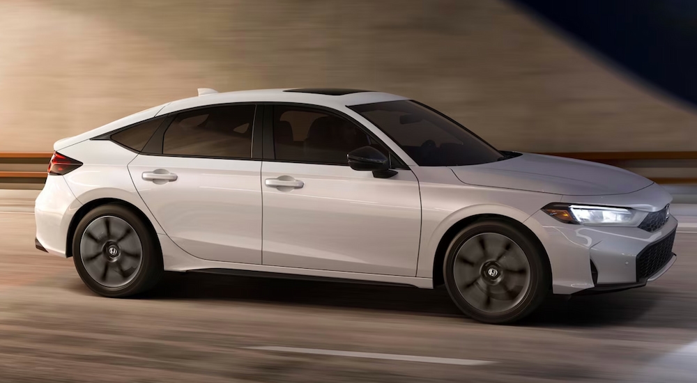 A white 2025 Honda Civic Hatchback Sport Touring Hybrid driving to a Honda dealer near Edmonds.