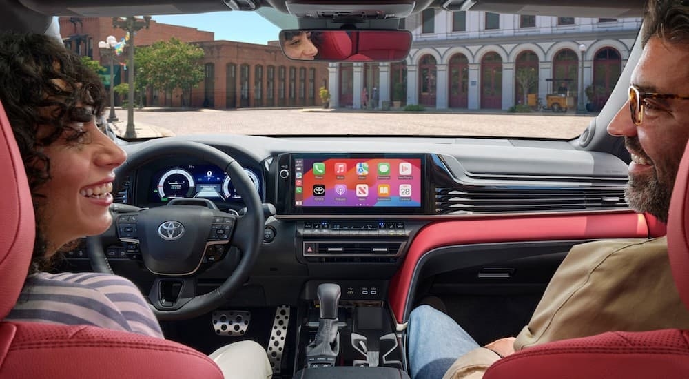 Two people sitting in the black and red interior cabin of a 2025 Toyota Camry.