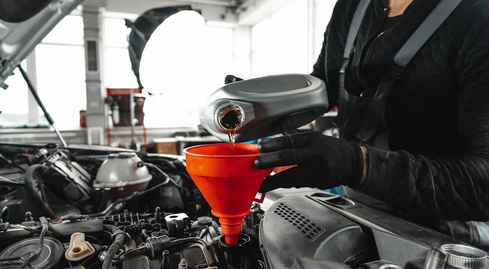 A mechanic adding new oil to a car's engine during an oil change near me.