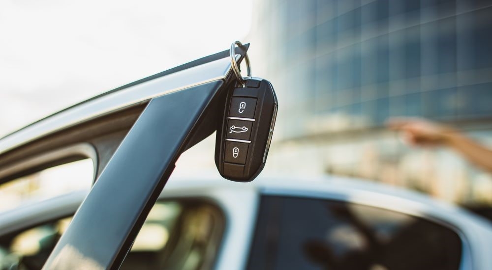 A close-up shows a key fob hanging on a car door.