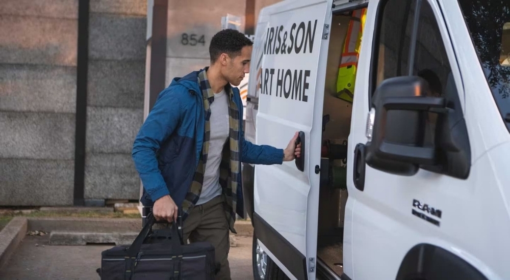 A person is shown closing the door on a white 2023 Ram ProMaster.