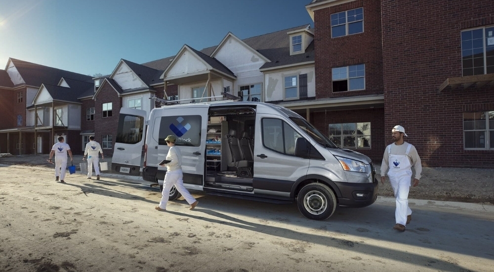 Workers are shown near a white 2023 Ford Transit.