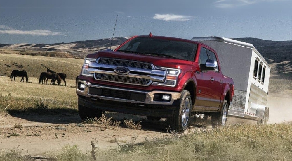 A red 2018 Ford F-150 is shown towing a trailer.