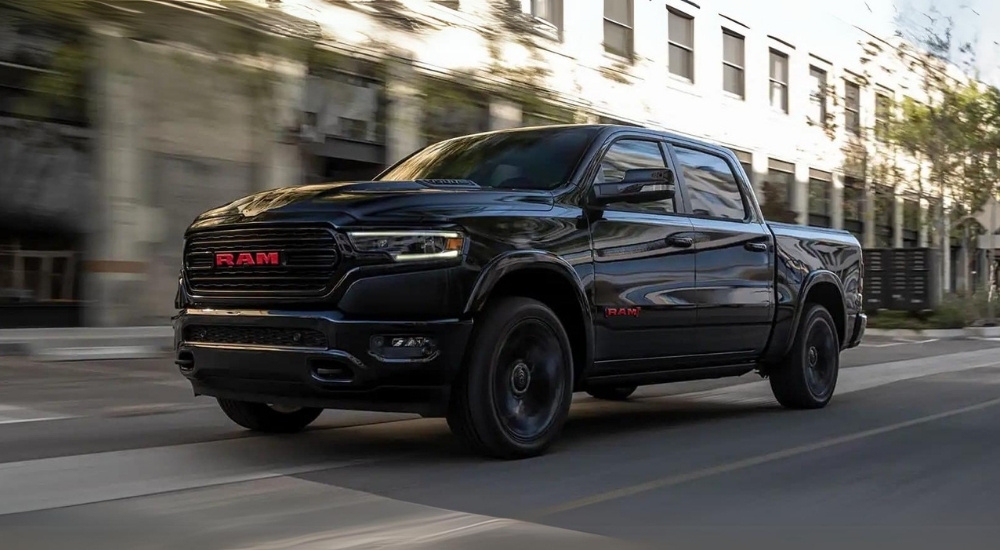 A black 2023 Ram 1500 Limited (RAM) Red Edition is shown driving on a city street.