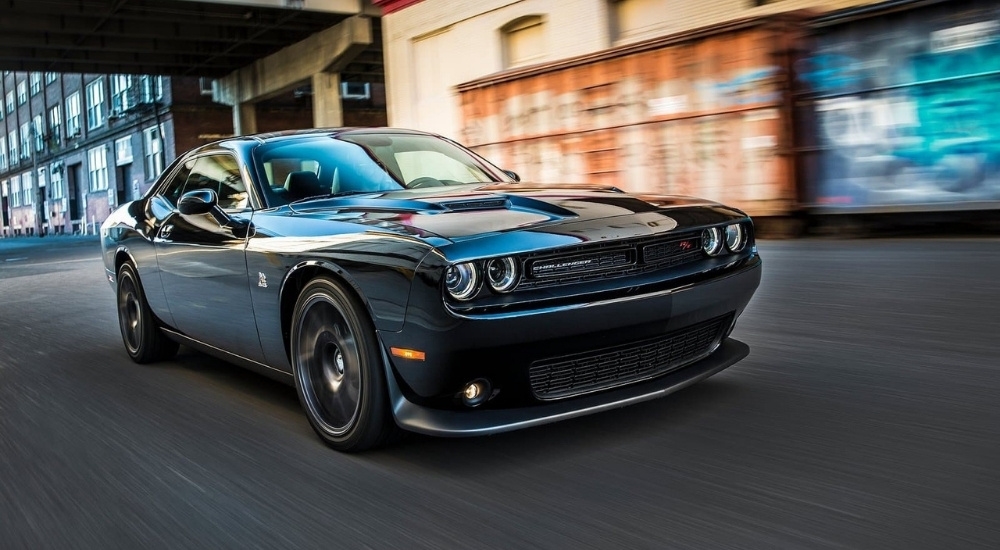 A black 2015 Dodge Challenger RT Scat Pack is shown driving on a city street.