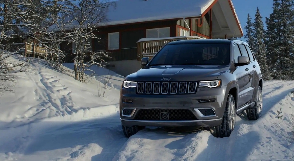 A grey 2021 Jeep Grand Cherokee is parked near a cabin.