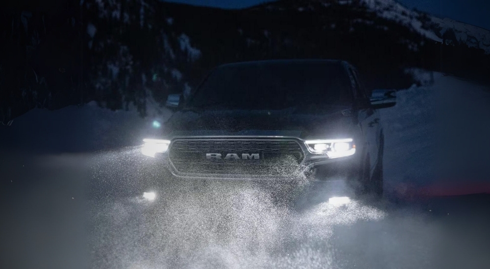 A grey 2023 Ram 1500 is shown driving through snow.