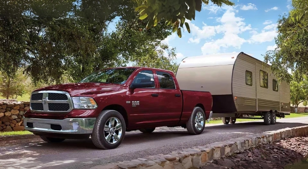 A maroon 2023 Ram 1500 Classic is shown towing a trailer.