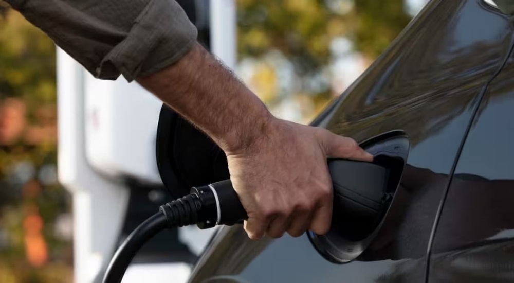 A person is shown charging a grey 2023 Chrysler Pacifica Hybrid.