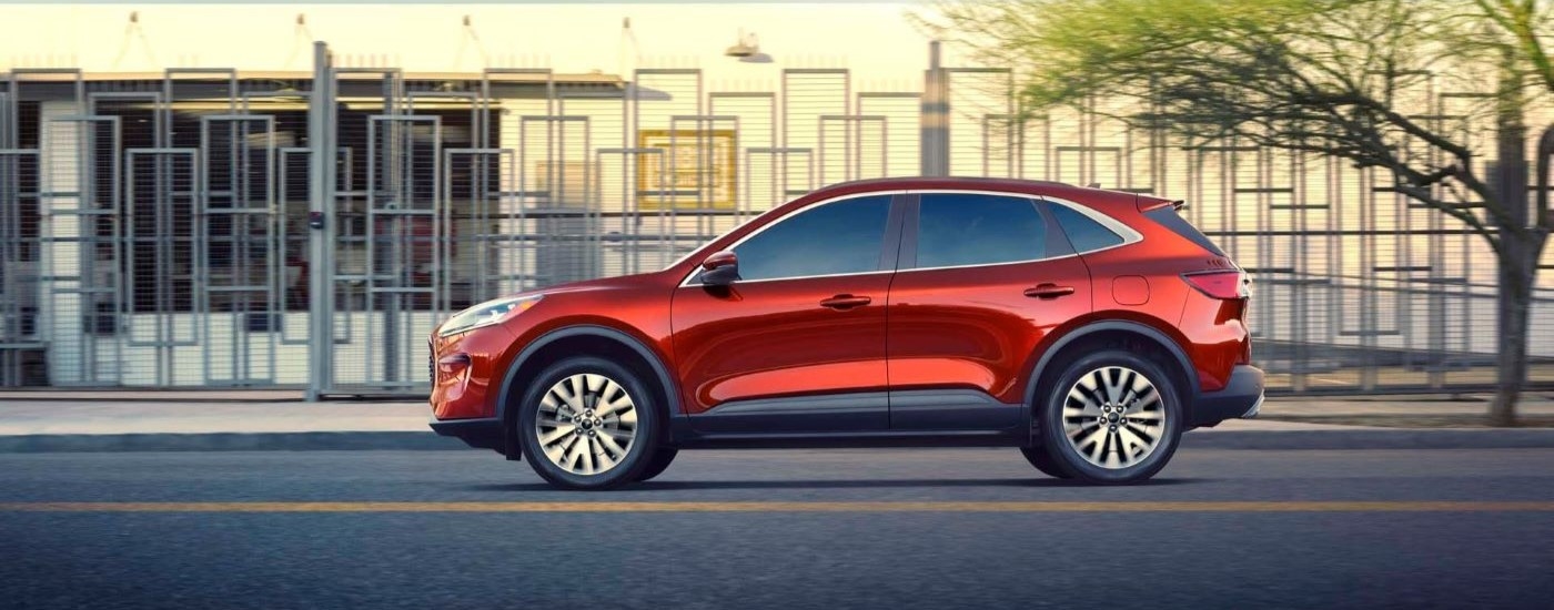 Side angle view of a red 2020 Ford Escape driving in a city.