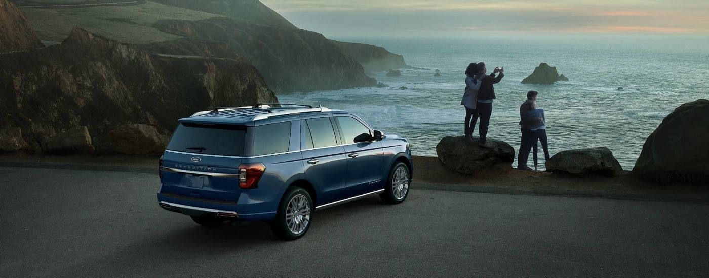 Rear angle view of a blue 2023 Ford Expedition parked by a shore.