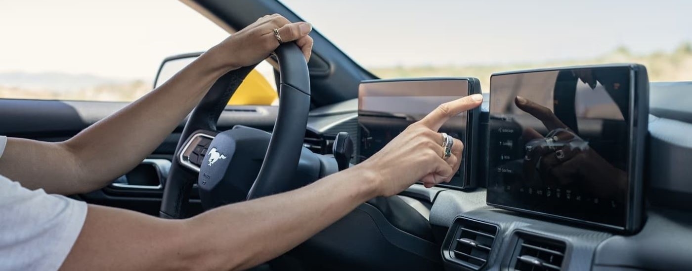 A person is shown using a touchscreen in a 2024 Ford Mustang.