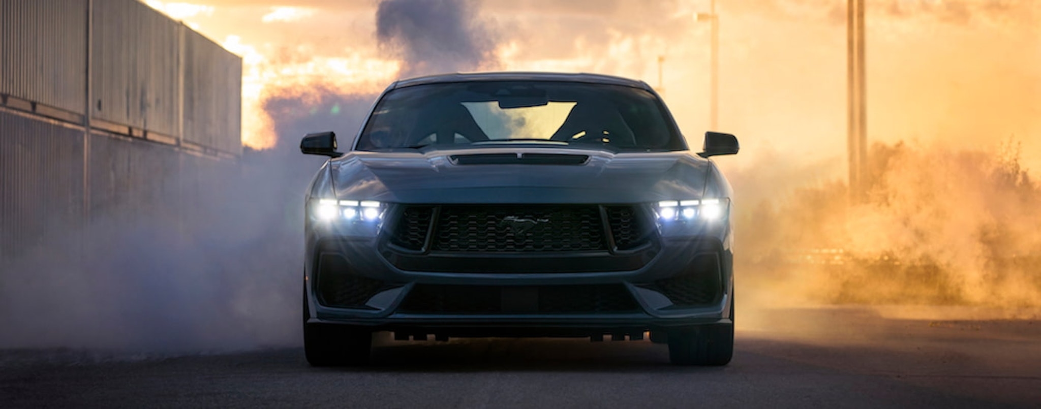 A blue 2024 Ford Mustang GT is shown from the front while doing a burnout after leaving a Ford dealer near Keene.