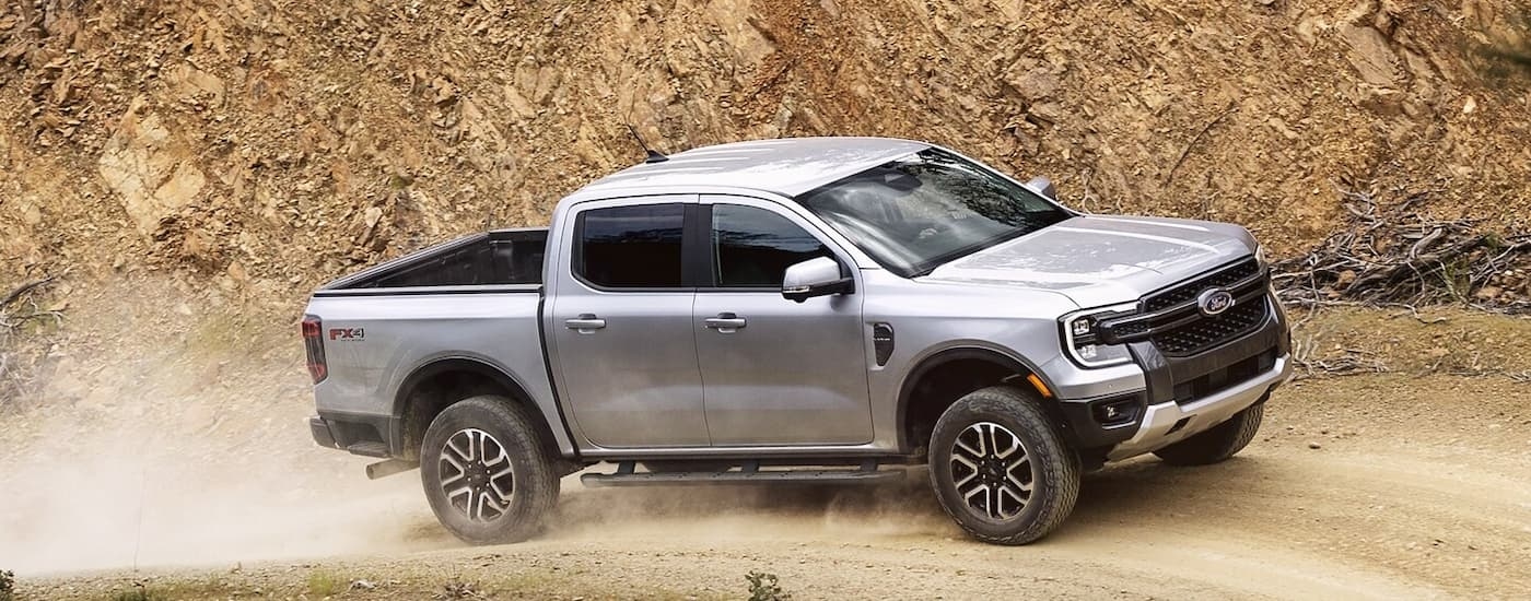 A silver 2024 Ford Ranger FX4 is off-roading on a dusty dirt road.