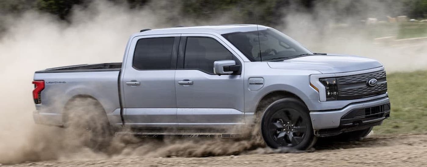 A silver 2024 Ford F-150 Lightning Lariat is shown from the side while off-road.