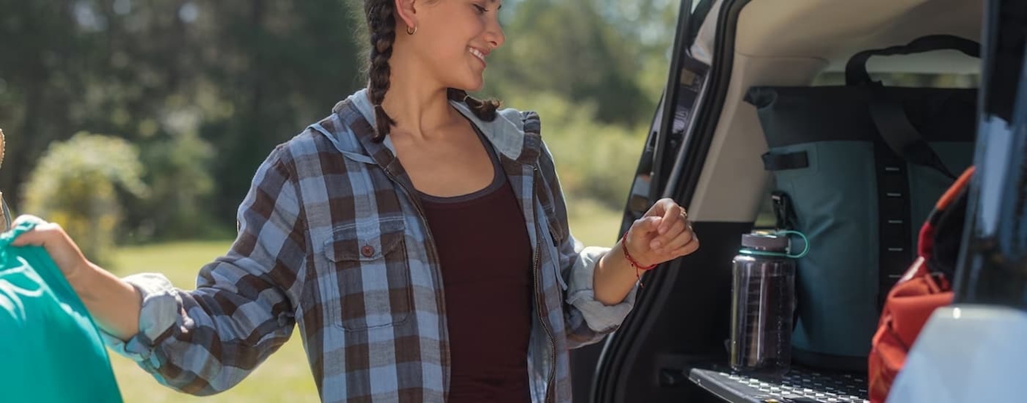 A woman is shown taking supplies out of the rear cargo area of a 2023 Ford Bronco Sport.
