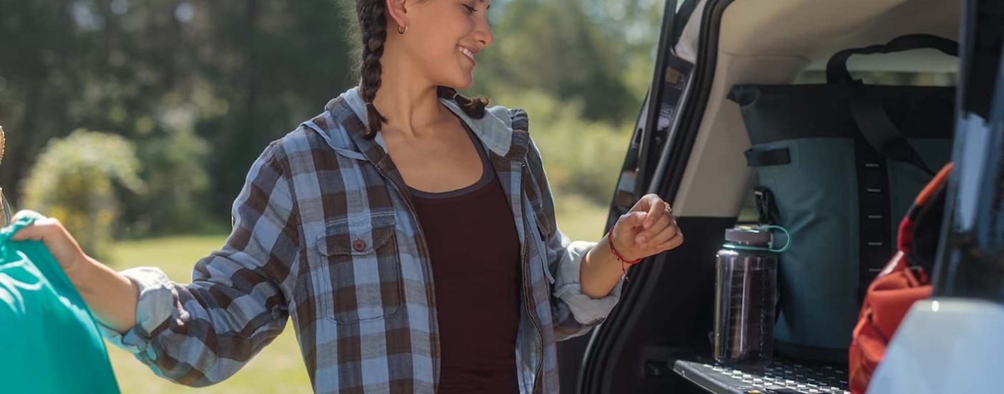 A woman is shown taking supplies out of the rear cargo area of a 2023 Ford Bronco Sport.