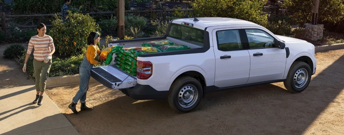 People are shown loading soil onto the bed of a white 2024 Ford Maverick.